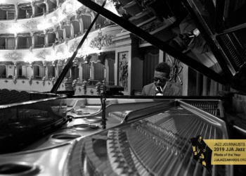 Closeup of the piano soundboard with Roy Hargrove at the keys in the background