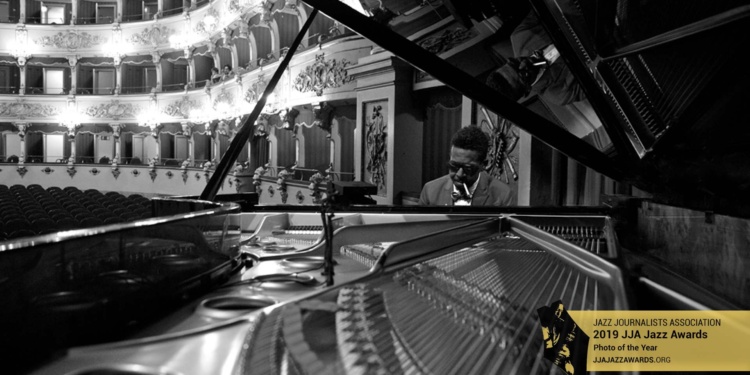 Closeup of the piano soundboard with Roy Hargrove at the keys in the background